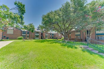 A tree with pink flowers is in front of a building.